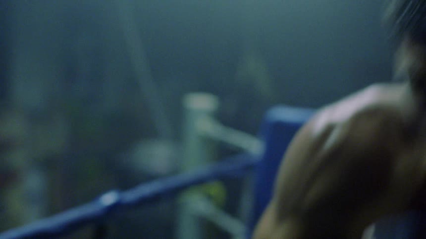 A shirtless boxer spars in a boxing ring