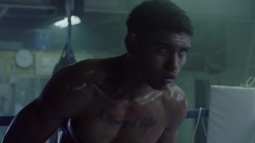 A boxer is moving around the dark ring