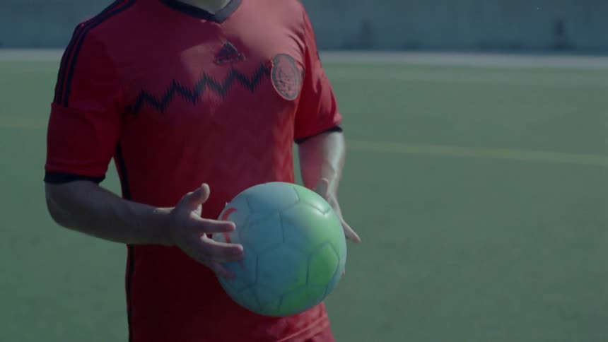 Soccer player walks across soccer field with ball