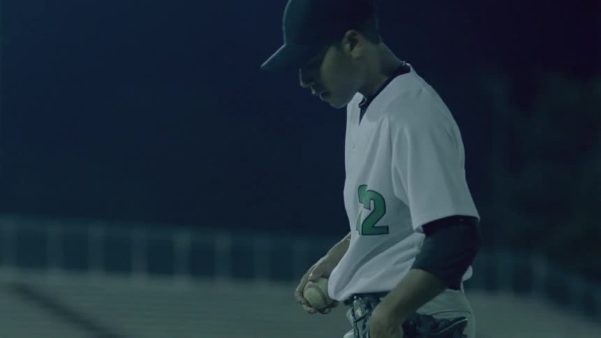 Man stands on a pitchers mound holding a ball and spits
