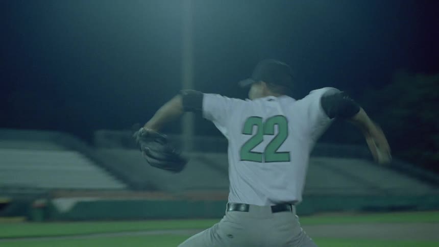 A pitcher winds up to throw at night