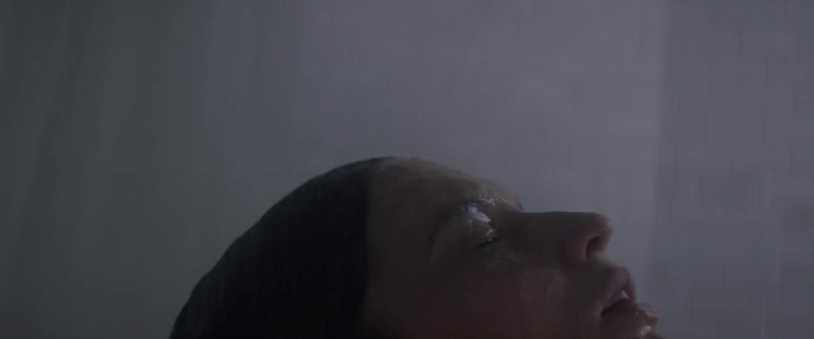 A woman is taking a shower in a dark bathroom