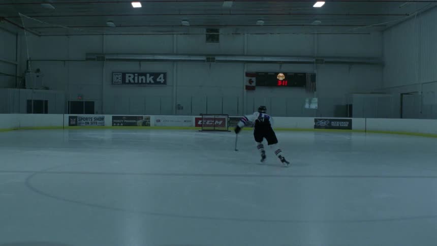 A hockey skater is skating down rink and around the goal