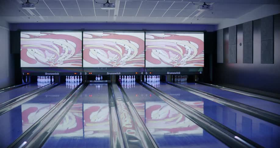 Man throws a bowling ball down a lane and misses pins