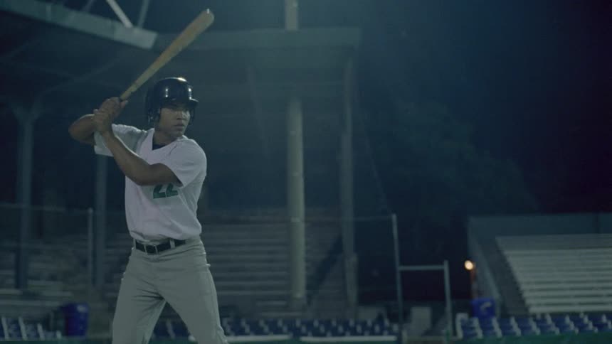 Batter hits baseball on baseball field at night