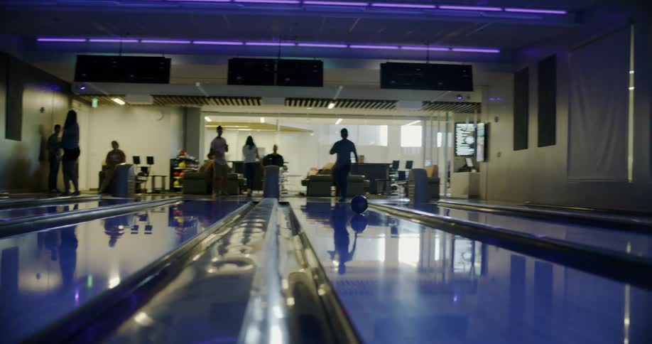 People bowl in a bowling alley