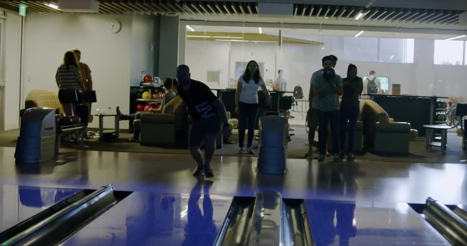 A man throws a bowling ball hoping for a strike