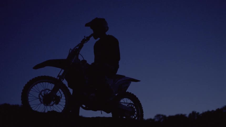 A man on a dirt bike parks atop a hill