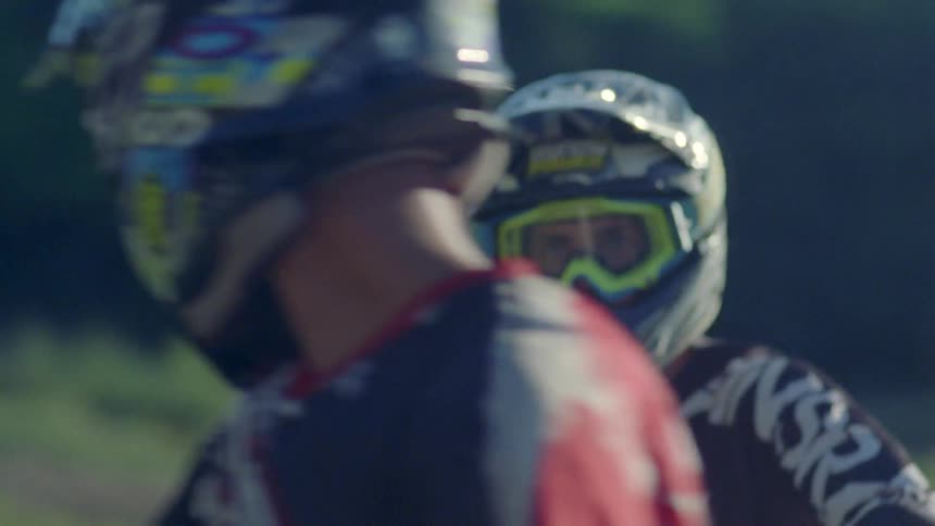 A motocross rider stares at another rider as he rides past him