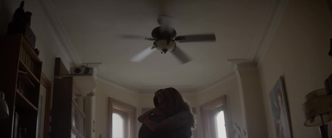 A couple dance close in a home during the day