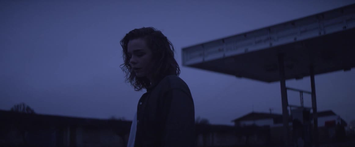 Woman stands outside at dusk