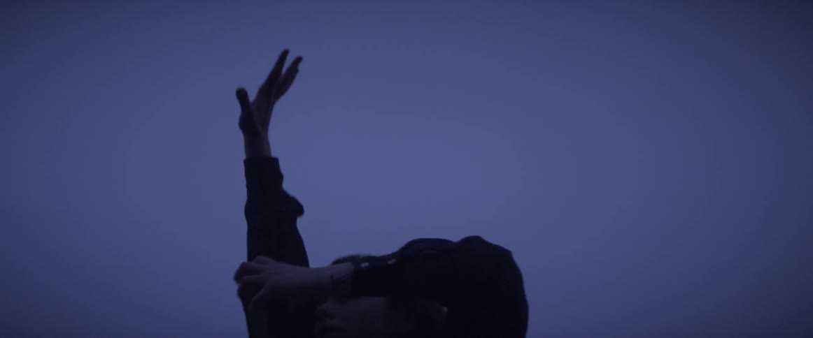 A woman is outside stretching her hands towards the sky