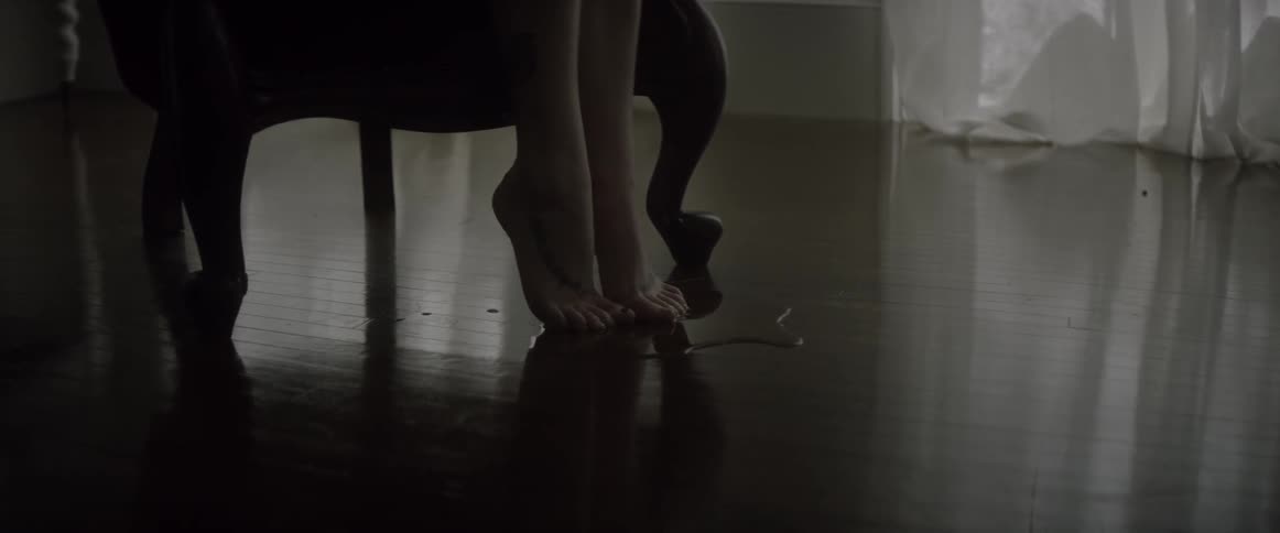 A lady with no shoes is sitting in a chair