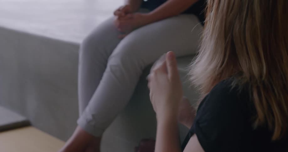 A woman is talking to friends using sign language as they sit indoors during the day