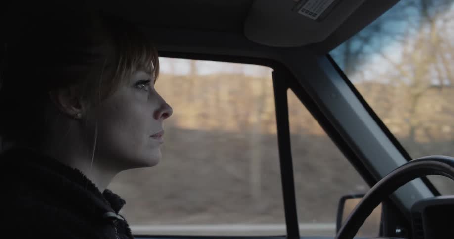 A woman drives a vehicle in a rural area