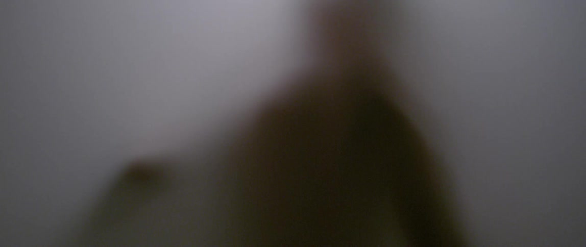 A blurry silhouette of a person behind a white canvas