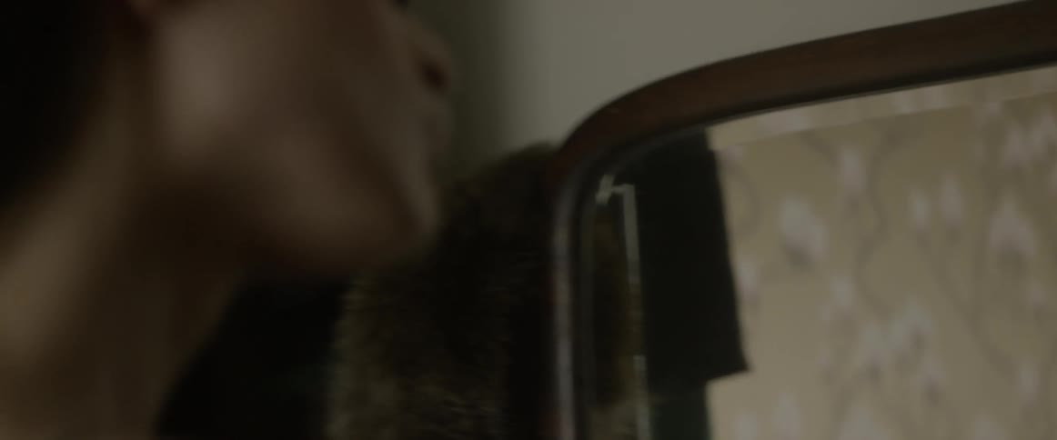 Woman applies makeup while looking in mirror