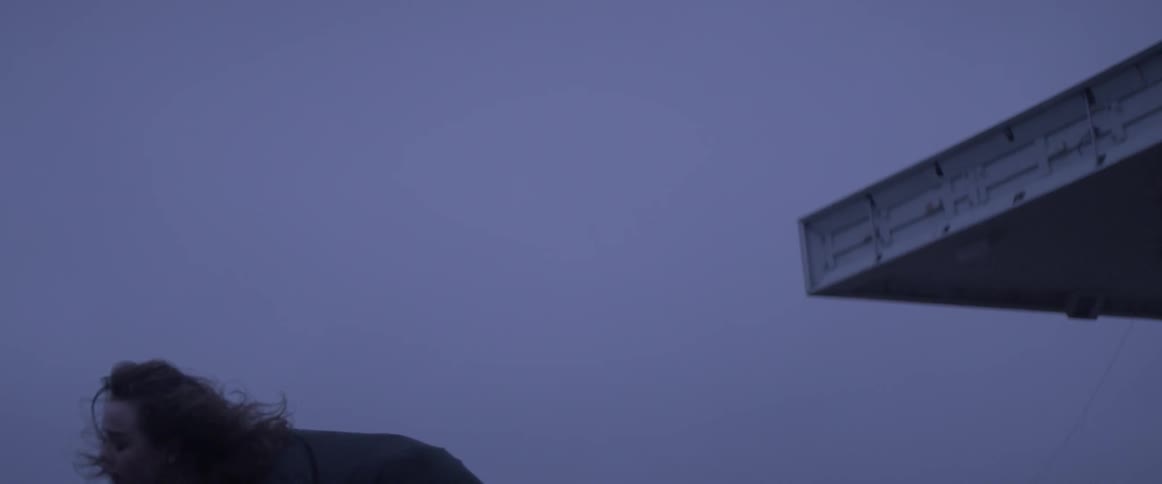 A woman is dancing wildly outside at dusk