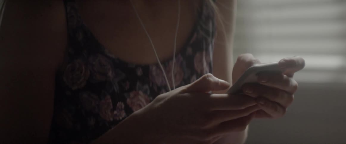 Woman taps on her cell phone as she holds it in her hands