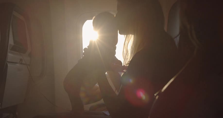 A woman is holding a baby on a plane