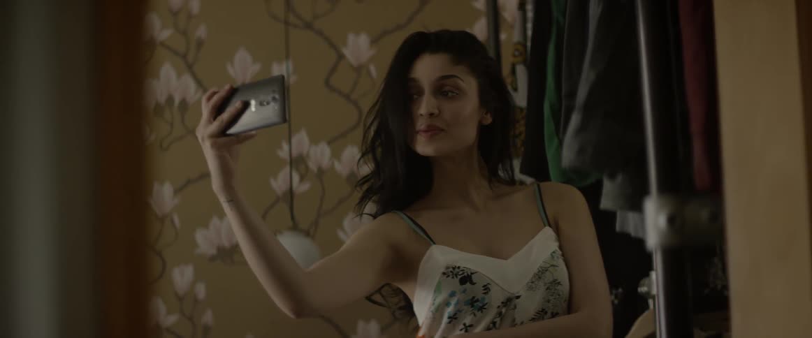 A woman smiles and takes a selfie