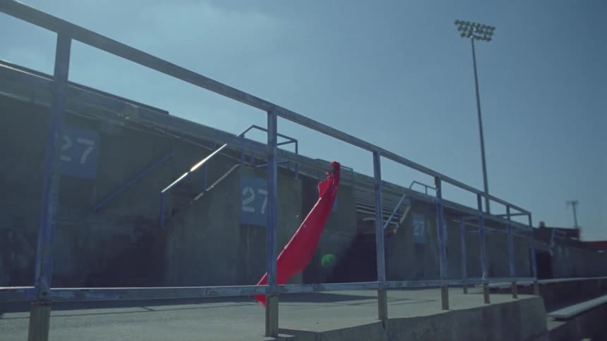 A red flag blows in the breeze as it hangs on a railing in an empty stadium