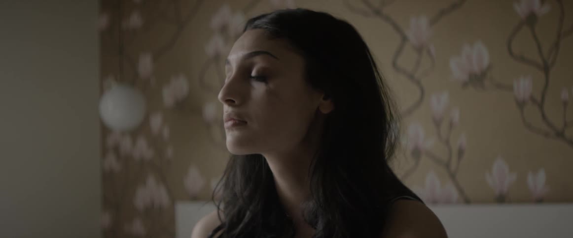 A woman sits up in bed and brushes her hair back