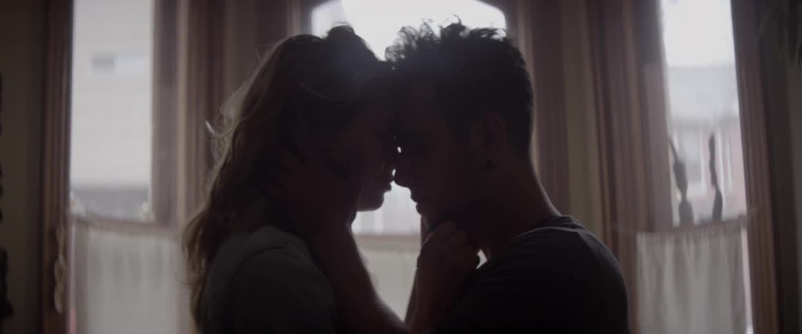 A couple are touching and cuddling in a room during the day