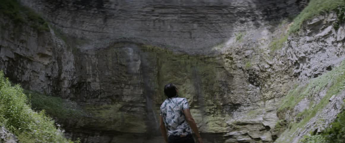 A man is walking towards a cliff on a sunny day
