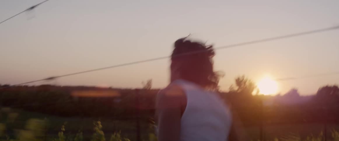 A man is running full speed down a dirt road between two open pastures
