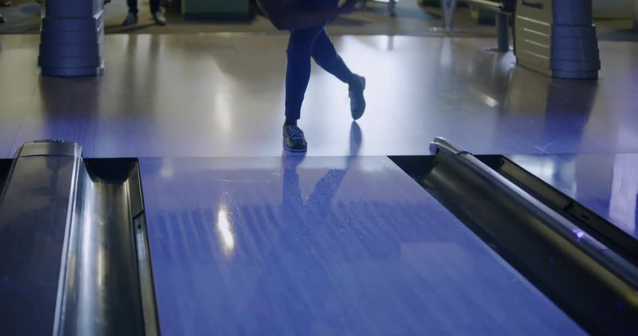 Person throws a bowling ball down a bowling lane