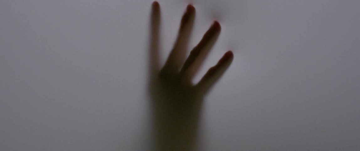 A hand is touching and pushing on an opaque surface