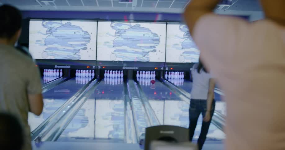 Woman rolls a bowling ball down the bowling lane