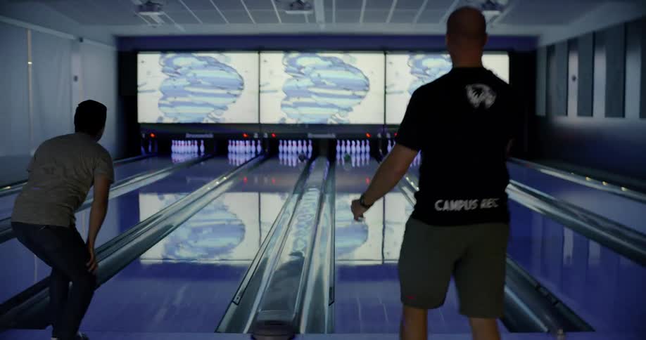 Two men bowl at the same time and high five