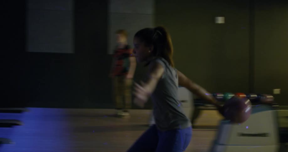 Woman throws bowling ball down a bowling lane