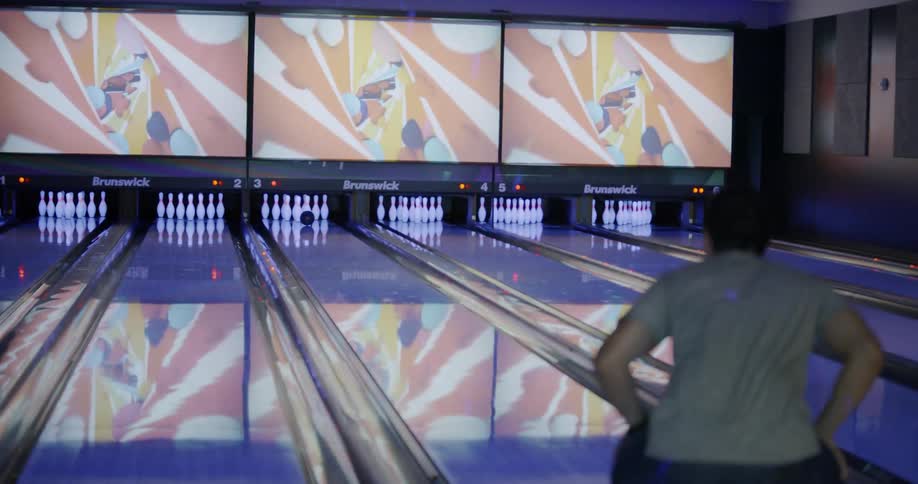 A man hits a strike and cheers with friends