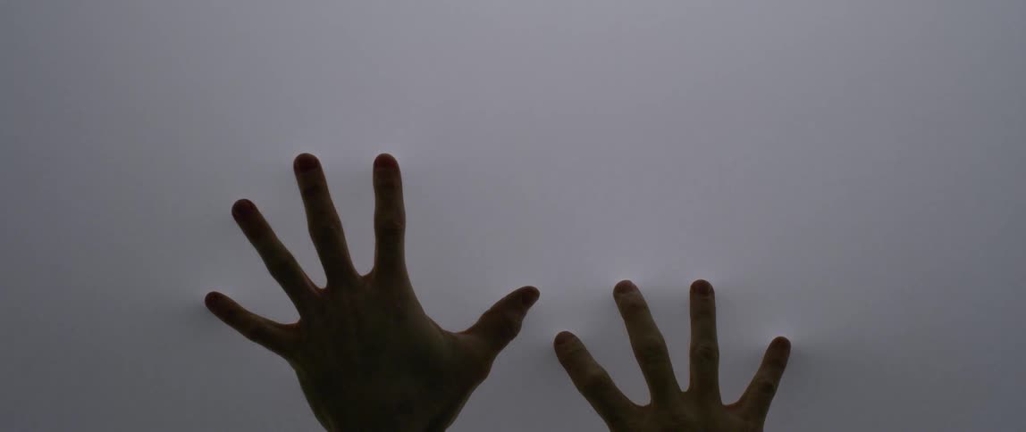 A person's hand moves pressing against a white wall