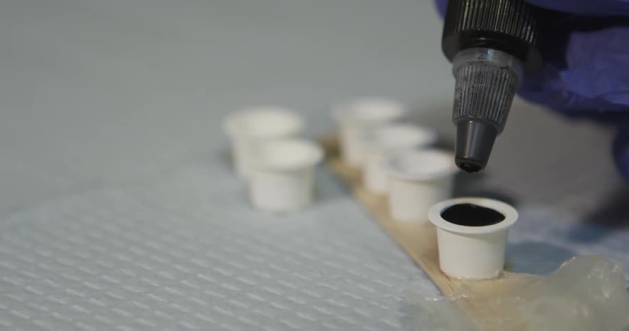 Gloved hands put a liquid into a container