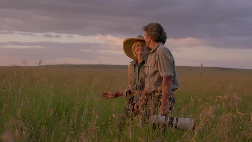 A man and woman are looking at the sunset on the plains