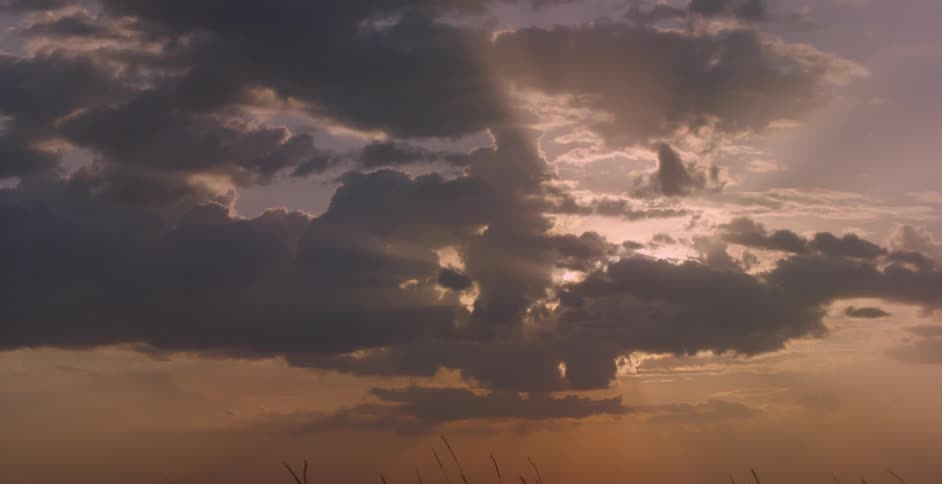 The sun is shining through the heavy clouds in the sky as it sets