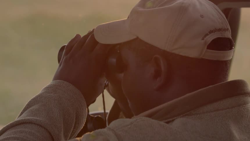 A man is using binoculars to look out of his vehicle