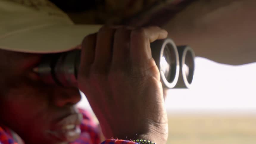 Man uses binoculars while looking out of vehicle