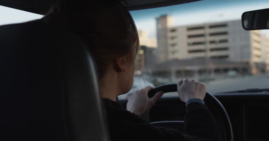 A woman drives a car down a city street