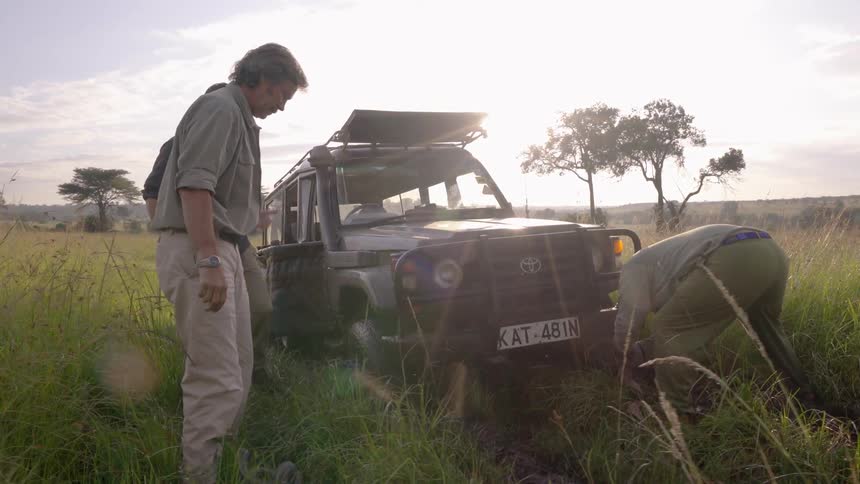 Men attach a tow rope to a car stuck in mud