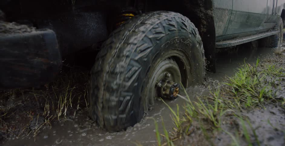 A jeep tire is spinning in the mud