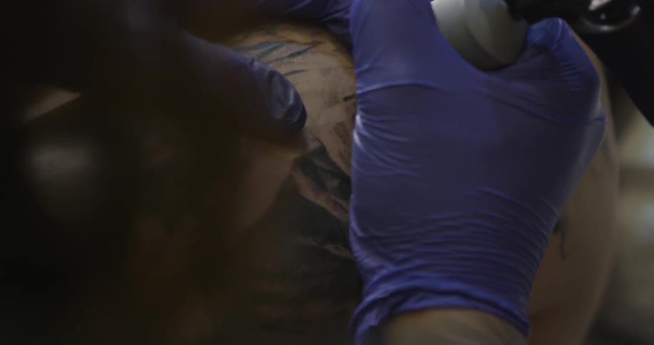 A tattoo artist works on a customer