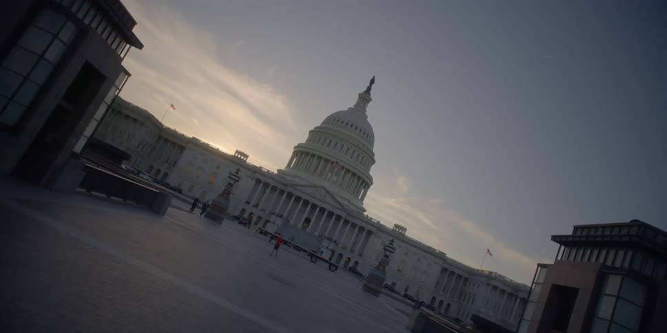Man walks in front of a capitol building at sunset