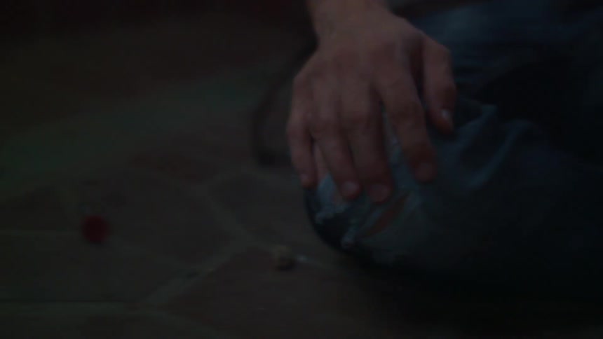A person sitting on the floor drops a needle from their hand