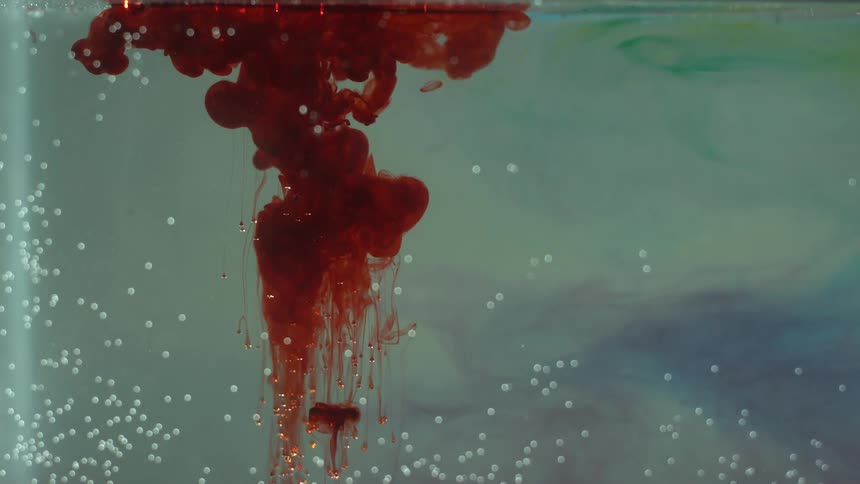 Red liquid flows to the bottom of a tank of water
