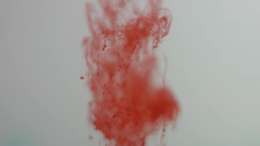 Red fluid falling in slow motion past a white backdrop